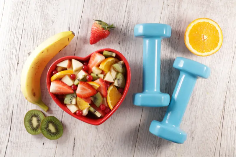 Health_and_fitness1 A bowl of fruit and two dumb bells next to the the bowl of fruit